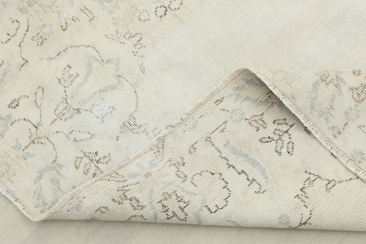 Corner of the rug folded back, revealing the reverse side of the hand-knotted cotton foundation.
