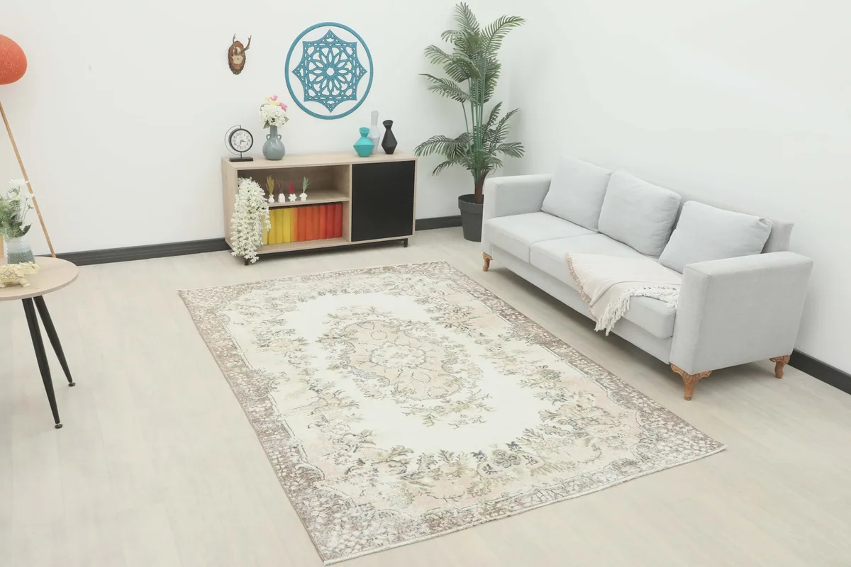 Ivory beige floral medallion rug displayed in a living room setting with a sofa and side table.