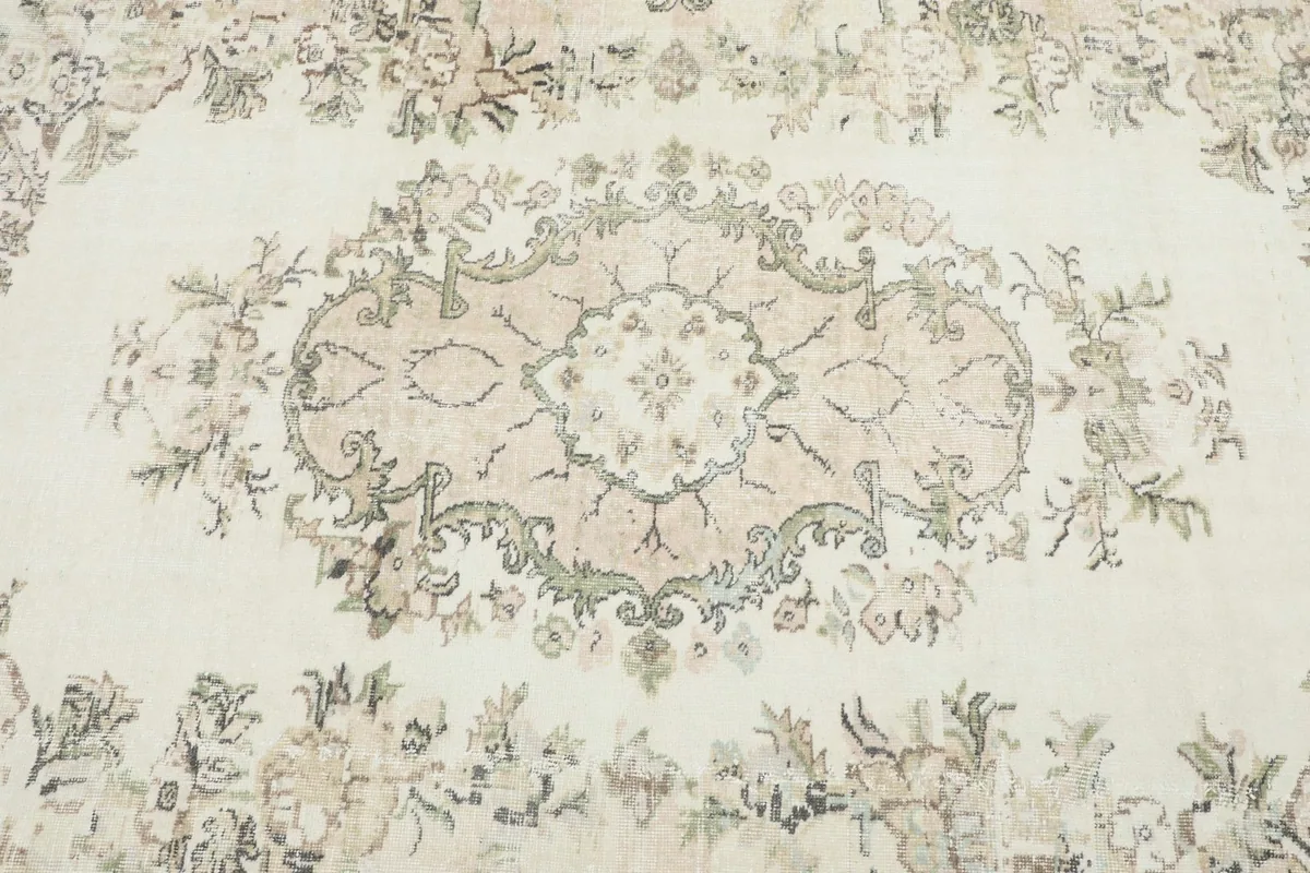 Detailed view of the central beige medallion and surrounding olive and brown floral motifs on the ivory field.