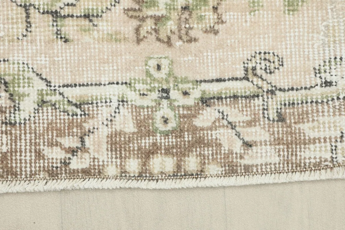 Detailed view of the rug's edge, showcasing the brown border pattern and short fringe.
