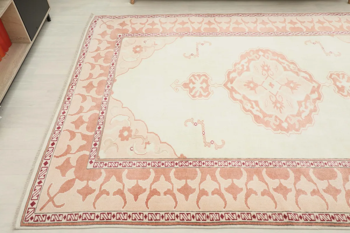 Angled view of the ivory and rose rug, highlighting the field and border patterns