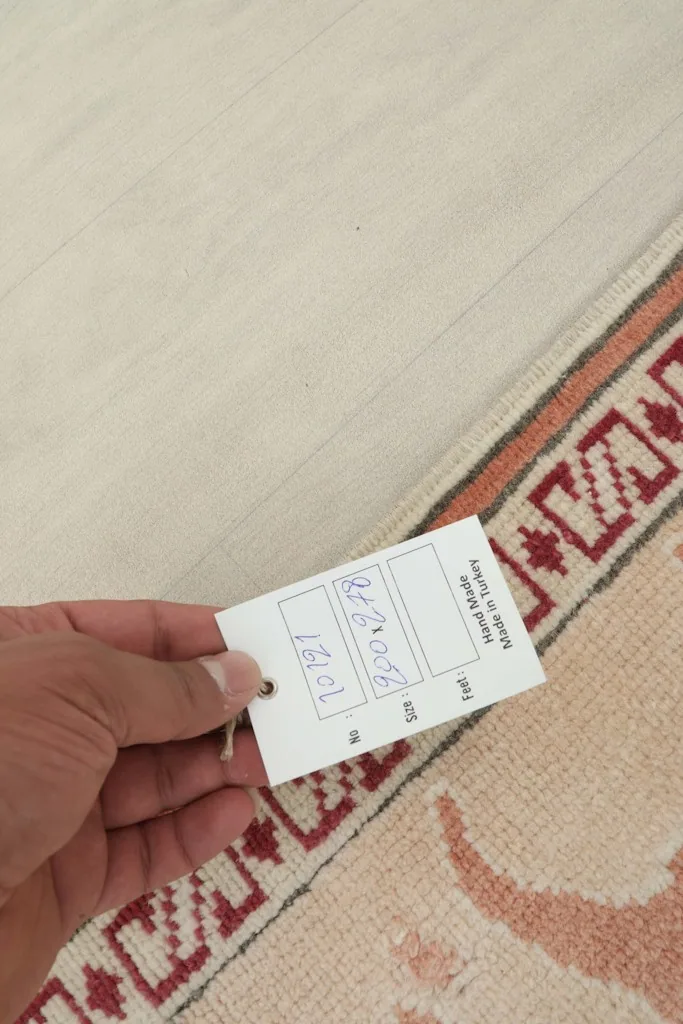 Hand holding a tag indicating the rug is hand made in Turkey