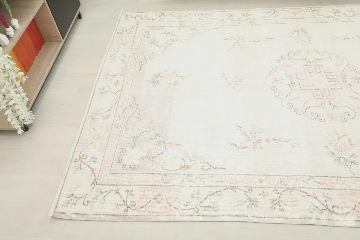 Angled view of the vintage rug, showing its placement next to a light wood and black cabinet.
