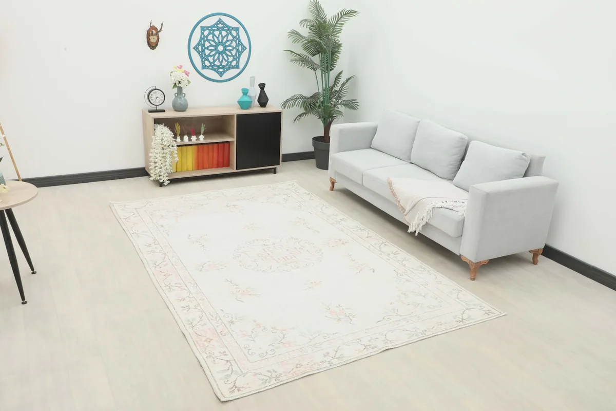 Ivory and rose vintage Anatolian rug displayed in a living room setting with a light gray sofa.