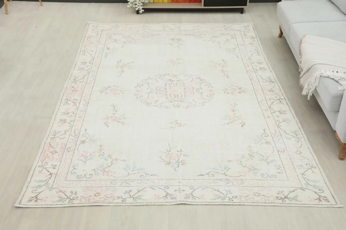 Overhead view of the 6'3" x 9'3" ivory vintage rug in a living room, next to a sofa.