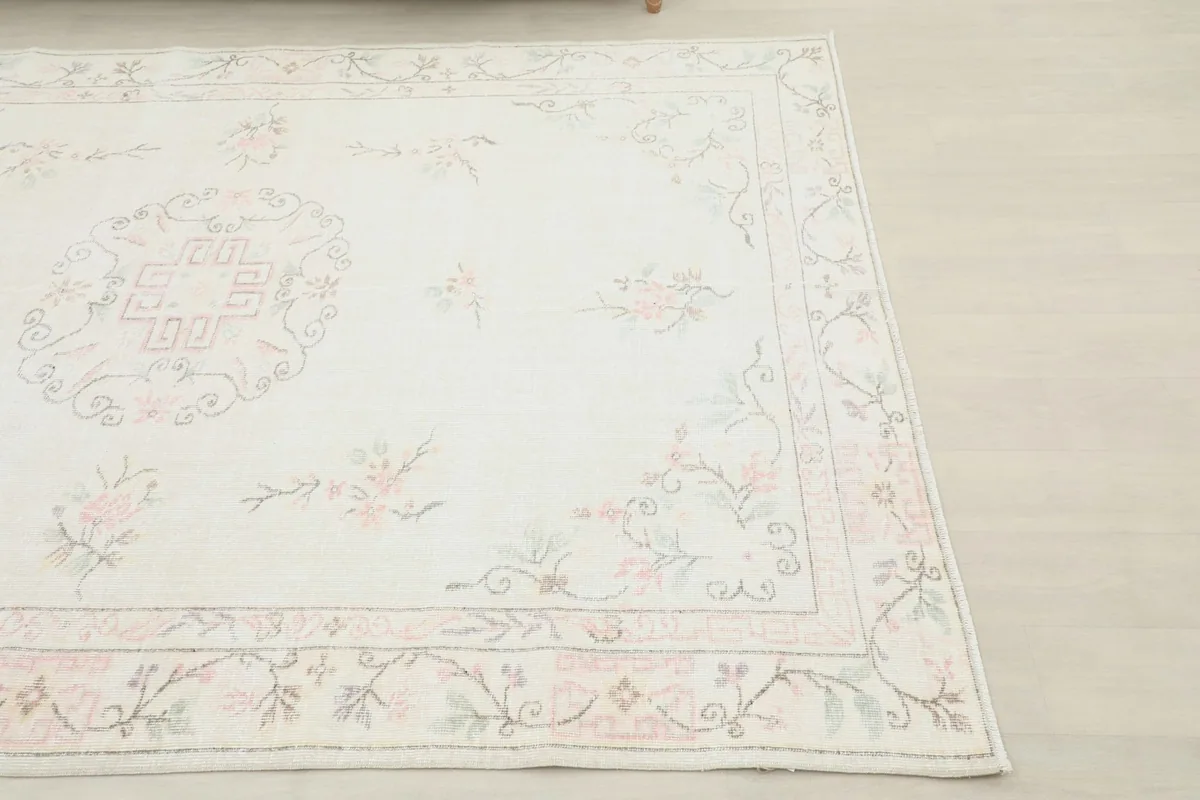 Close-up detail of the rug's corner, highlighting the rose and green floral border design.