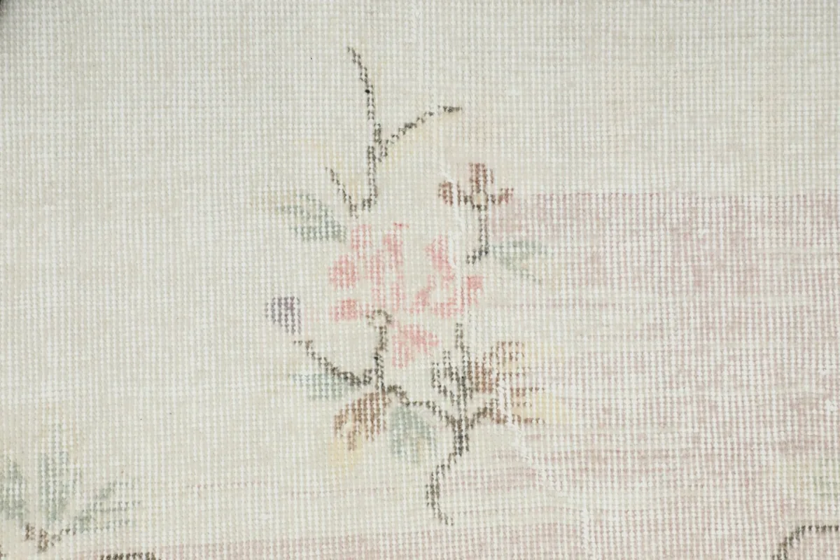 Extreme close-up view of the low wool pile and the hand-knotted texture of a rose floral element.