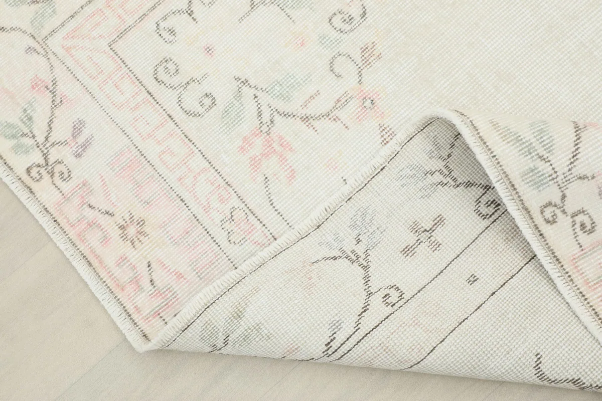 Corner of the rug folded back, showing the back of the hand-knotted cotton foundation.