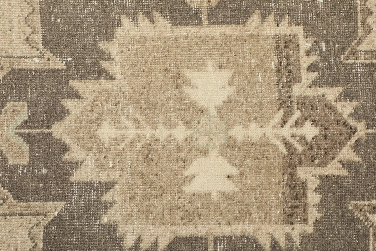 Tight detail shot of a complex geometric pattern and natural wear on the rug pile.
