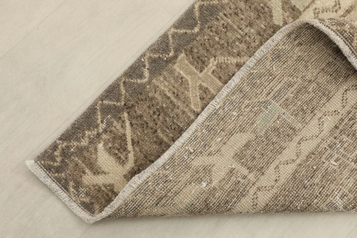 Folded corner of the rug revealing the backside and construction of the hand-knotted wool pile on cotton.