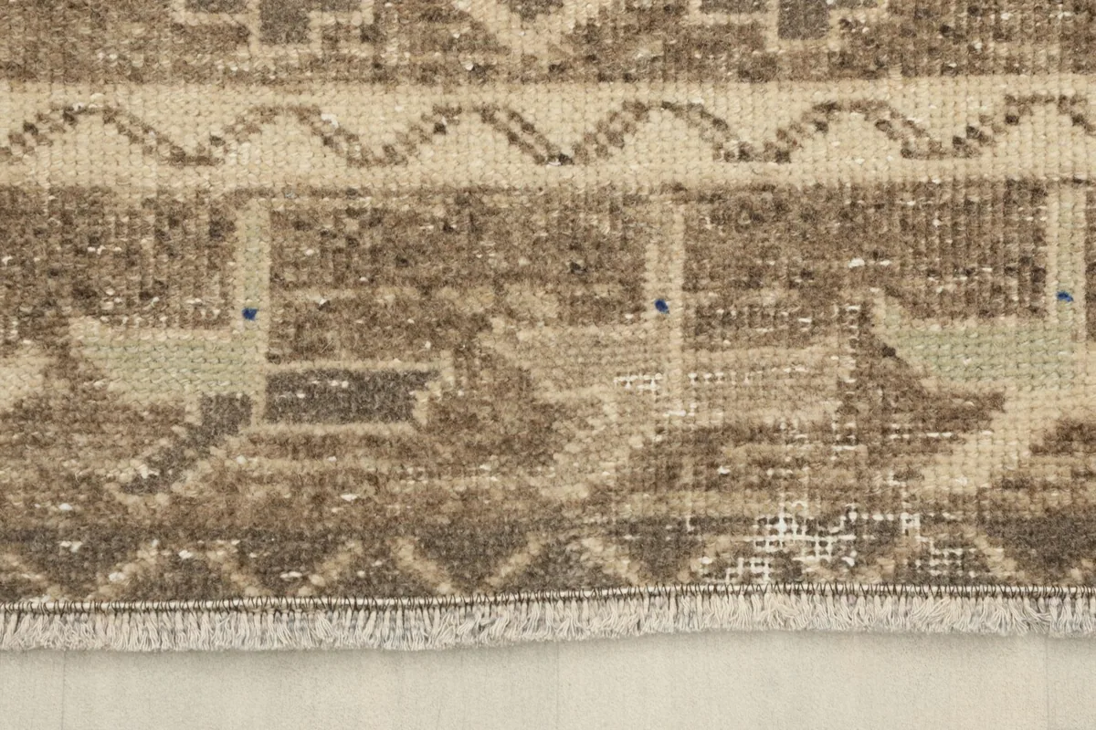 Detailed view of the rug's short fringe and woven edge, showing slight variations.