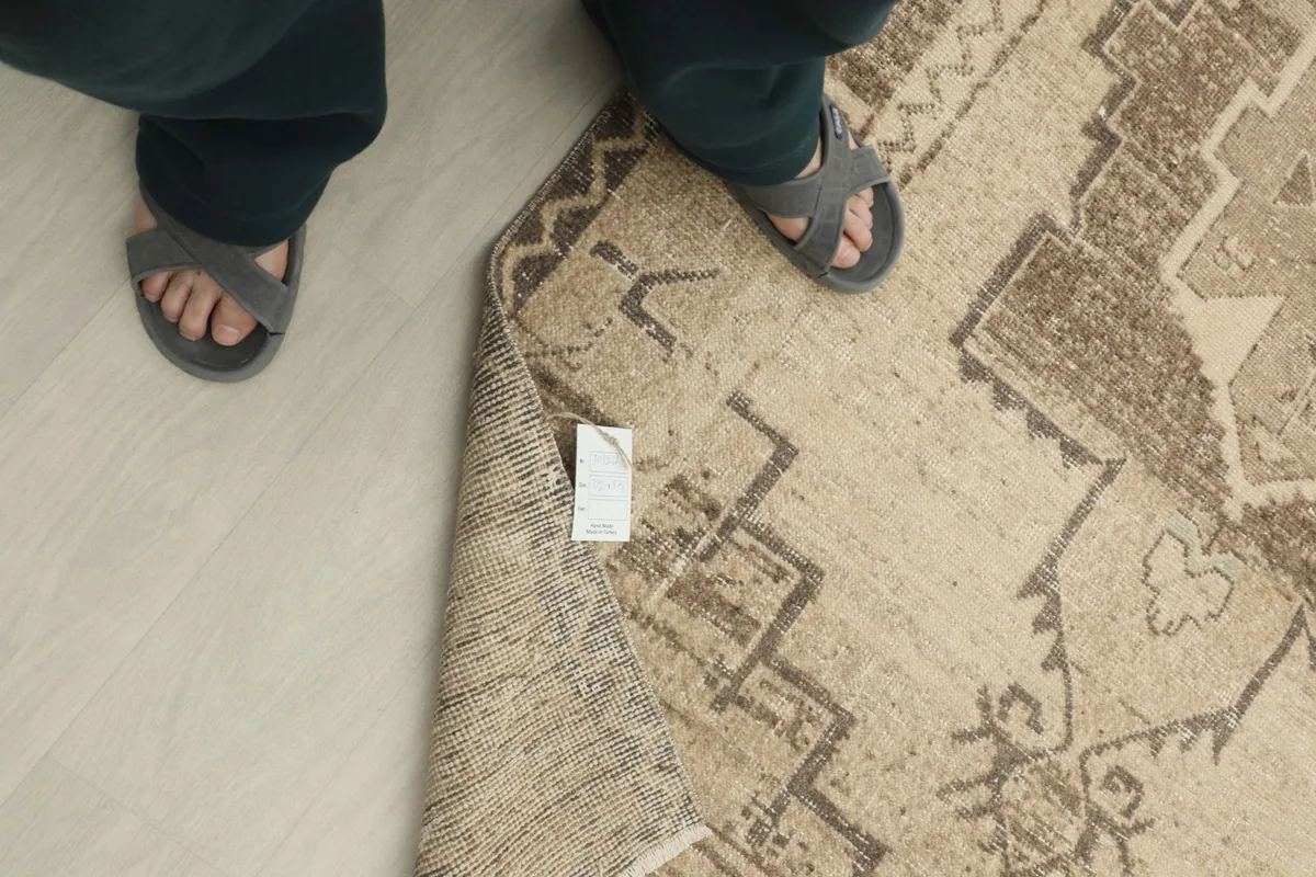 Overhead view with feet for scale, showing the texture and pattern of the vintage runner rug.