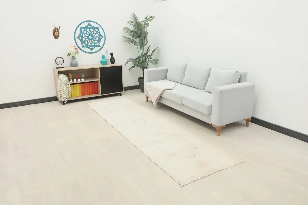 Ivory geometric runner rug in a living room setting with a sofa and cabinet, showing its scale.