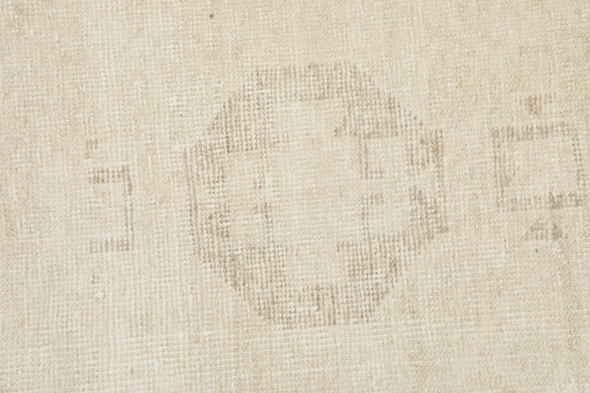 Close-up of the subtle texture and faded geometric design in the middle section of the ivory runner.