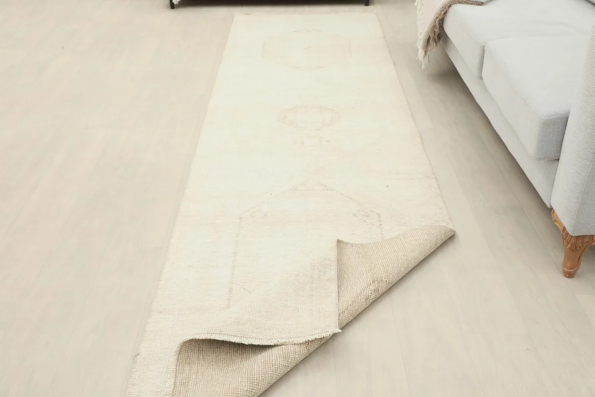 The ivory runner partially folded to reveal the underside, showcasing its construction in a room setting.