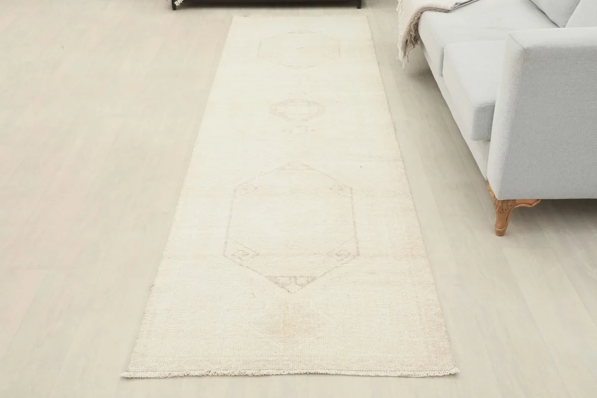 Overhead view of the full ivory geometric runner rug laid out in a room, showing its length and pattern.