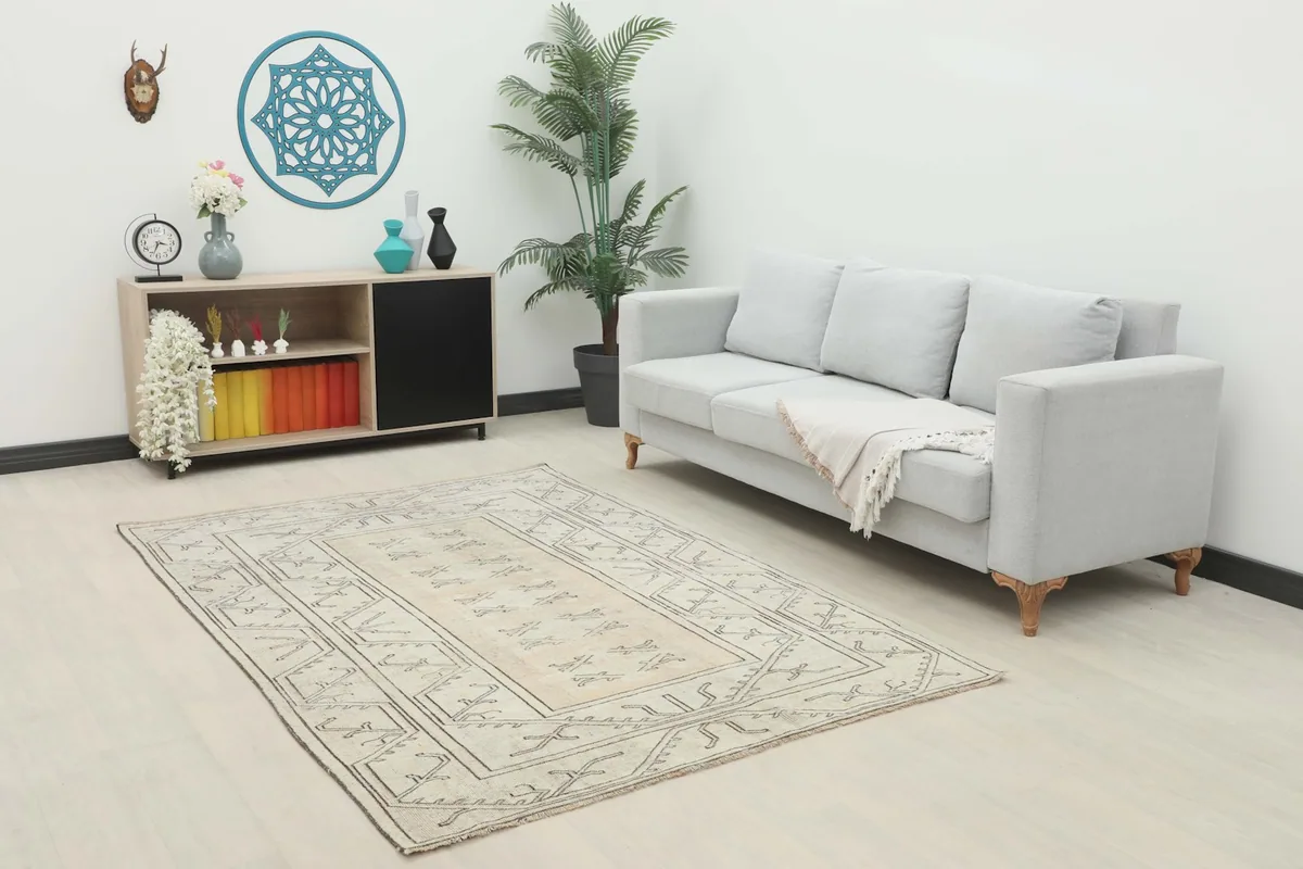 Beige and charcoal tribal rug placed in a living room setting with a light gray sofa