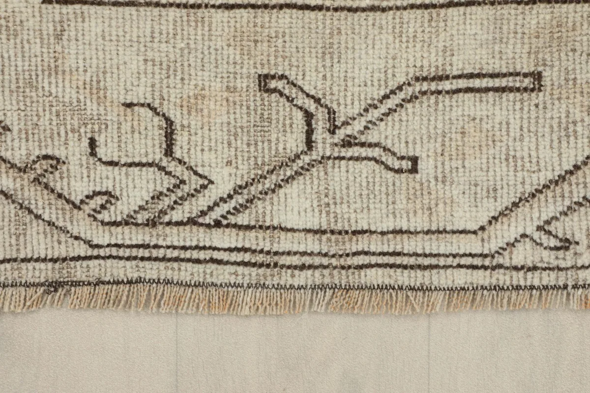 View of the rug's edge, showing the short, natural wool fringe and border detail