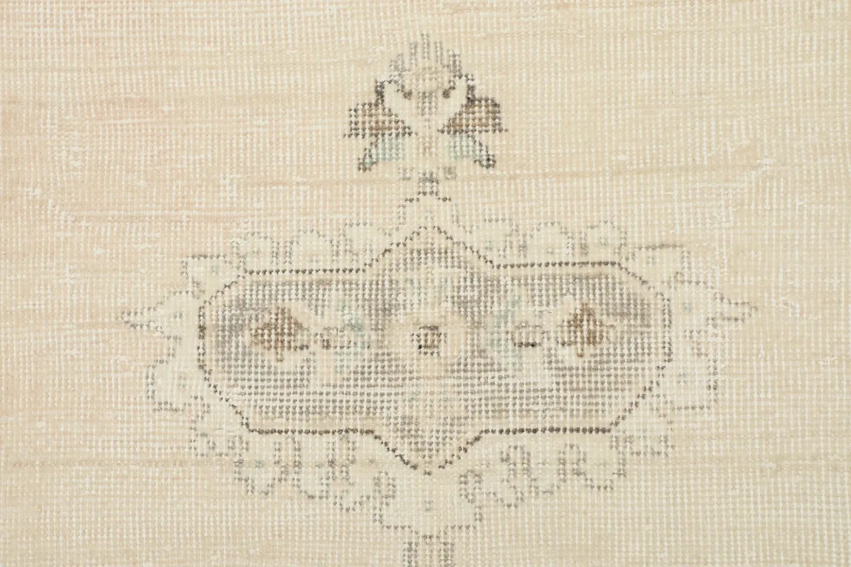 Detailed view of a small decorative motif within the ivory field of the vintage rug