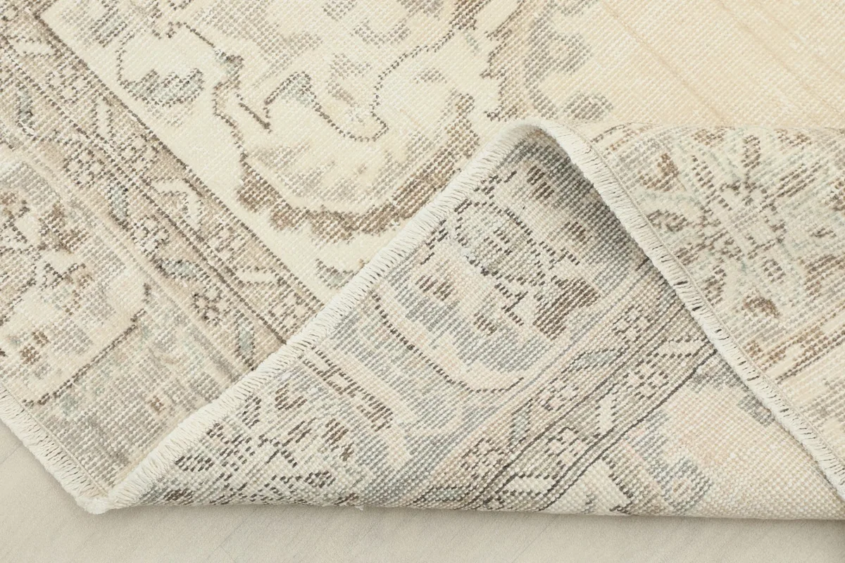 Corner of the rug folded back, revealing the hand-knotted cotton foundation and reverse side