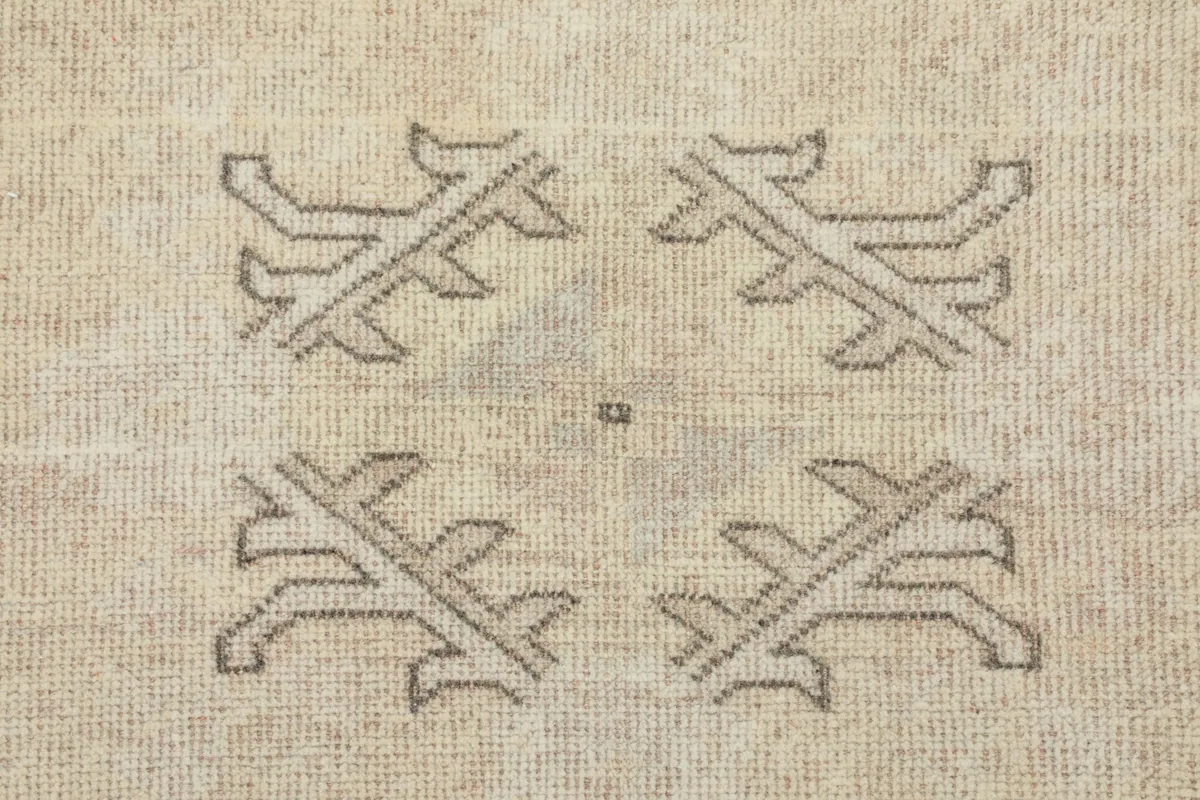 Detailed close-up of the geometric motifs in the central field of the rug, showing the hand-knotted wool texture.