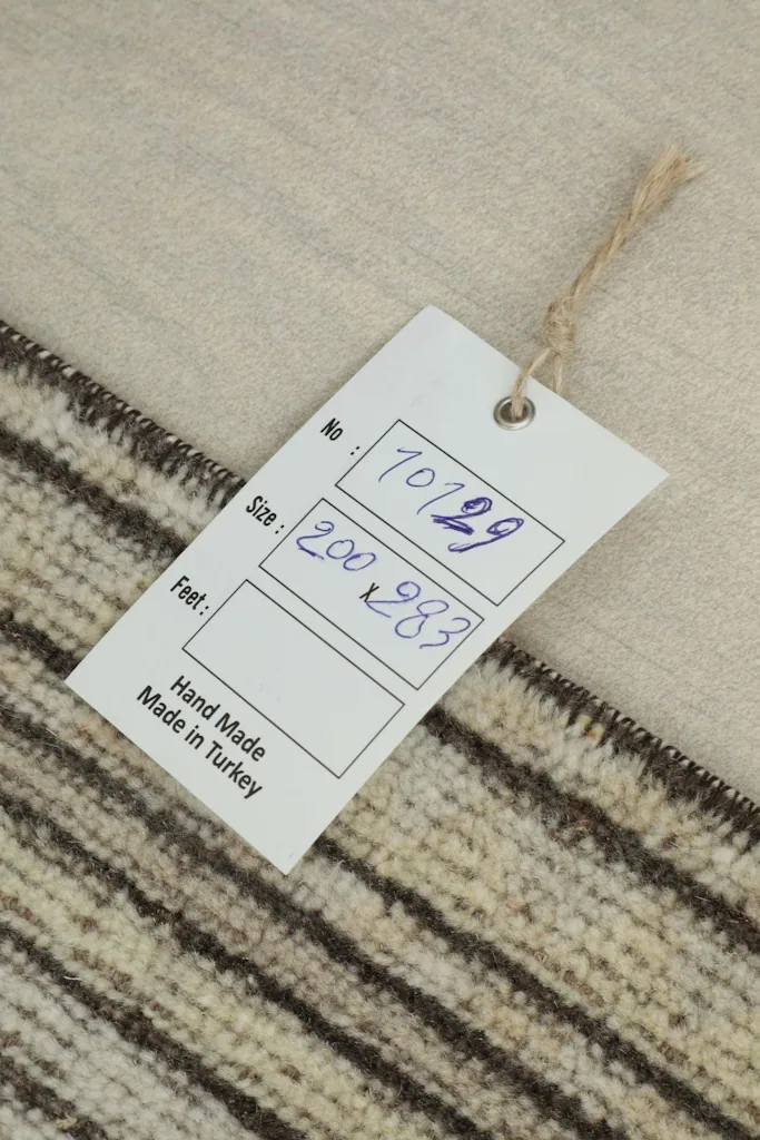Close-up of the rug's reverse side with a tag indicating 'Hand Made in Turkey' and its dimensions.