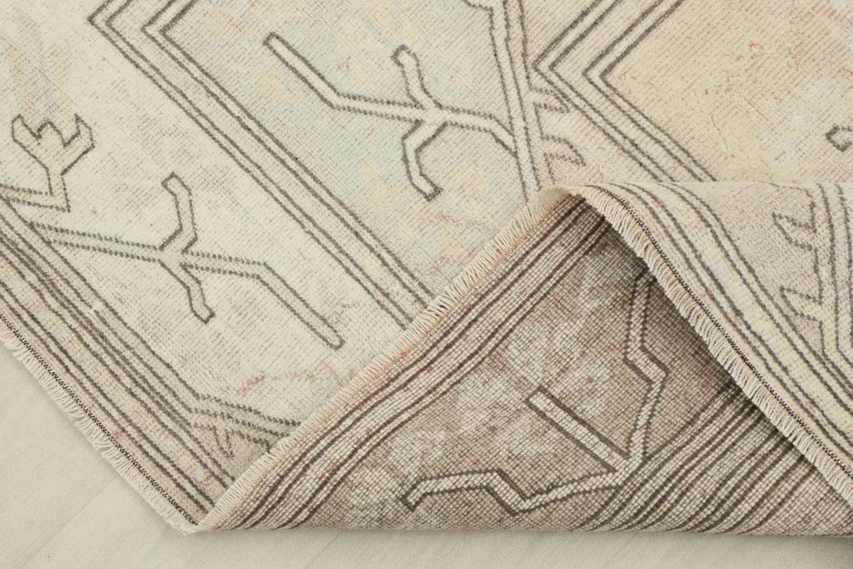 Corner of the rug folded back to reveal the density of the wool pile and the cotton foundation.