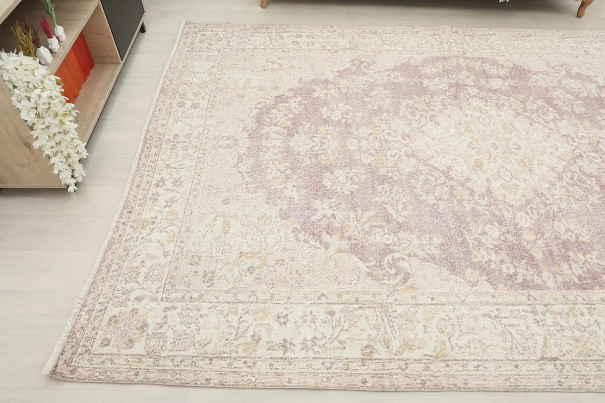 Angled view of the upper left corner of the rug in a room, displaying the subtle floral motifs