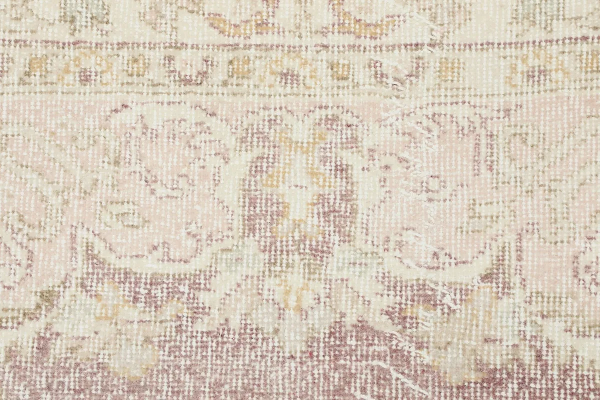 Close-up of the rug's texture and faded pattern, showing the hand-knotted wool pile and cotton foundation