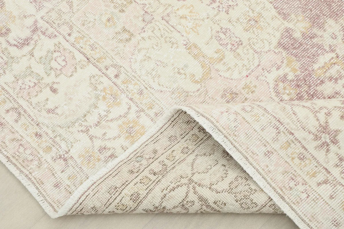 Corner of the rug folded to reveal the backside, showing the hand-knotted construction and cotton foundation