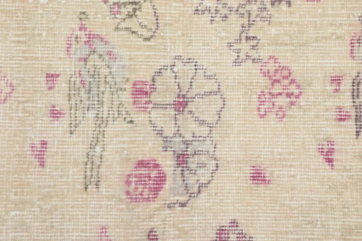 Detailed close-up of the hand-knotted wool pile, showing faded rose and gray motifs