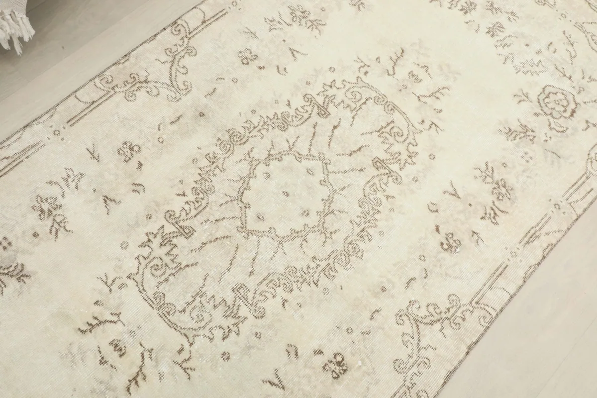 Detailed view of the central medallion and surrounding floral patterns on the ivory rug