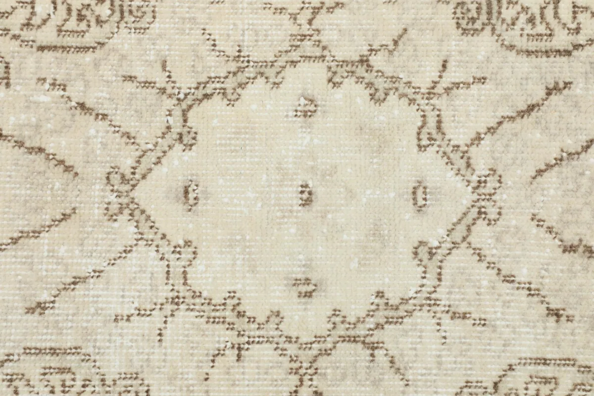 Macro shot of the low pile and intricate knotting of the ivory and beige vintage wool rug