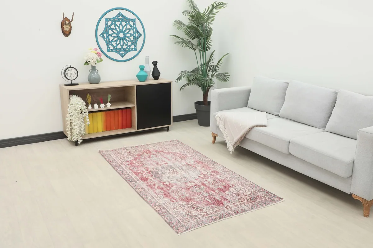 Vintage red and gray Anatolian rug displayed in a living room setting with a sofa and cabinet