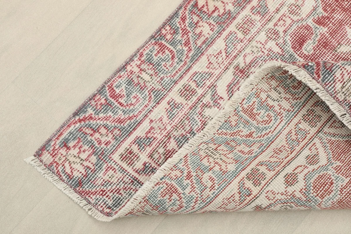 Corner of the rug folded back, showing the cotton foundation and the reverse side of the hand-knotted weave