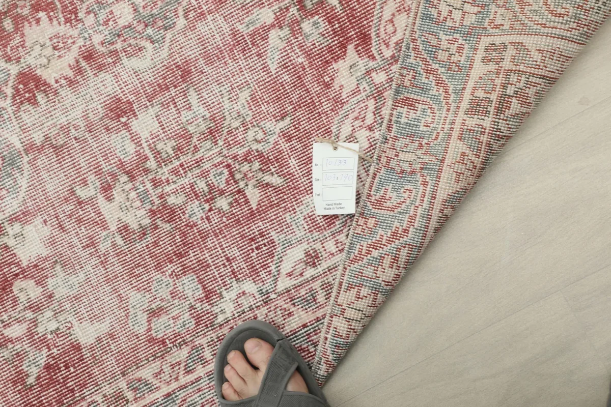 View showing a foot next to the rug to illustrate its scale and the texture of the low pile