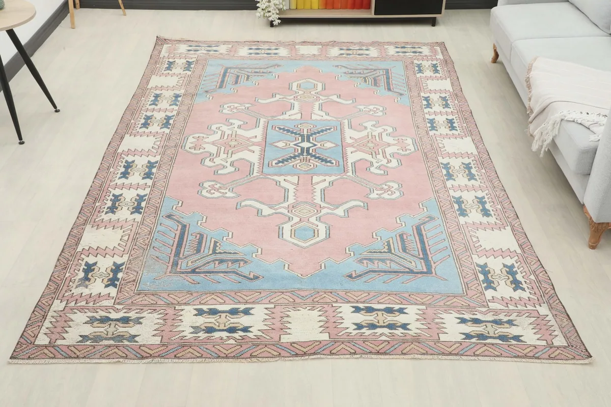 Full room view of the large pink and blue vintage rug from a wider perspective