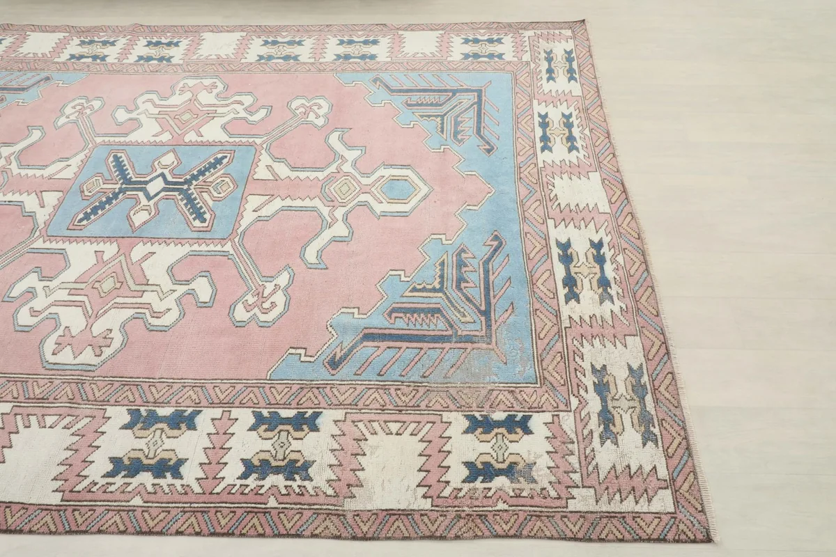 Close-up of the corner of the rug, showing the pink field and blue border details