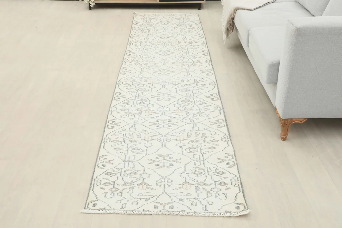 Full view of the runner rug laid out in a minimalist room, next to a sofa