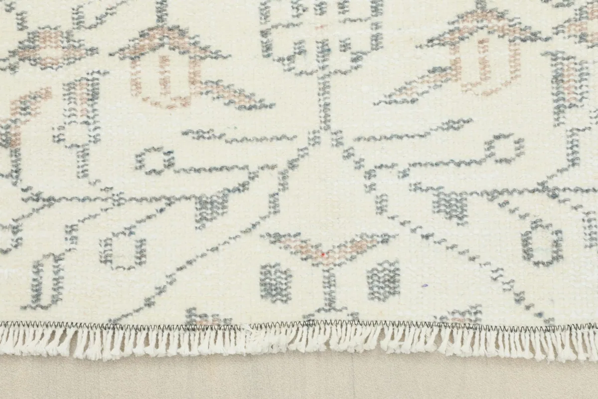 Close-up of the rug's short, natural cotton fringes and the edge of the pattern