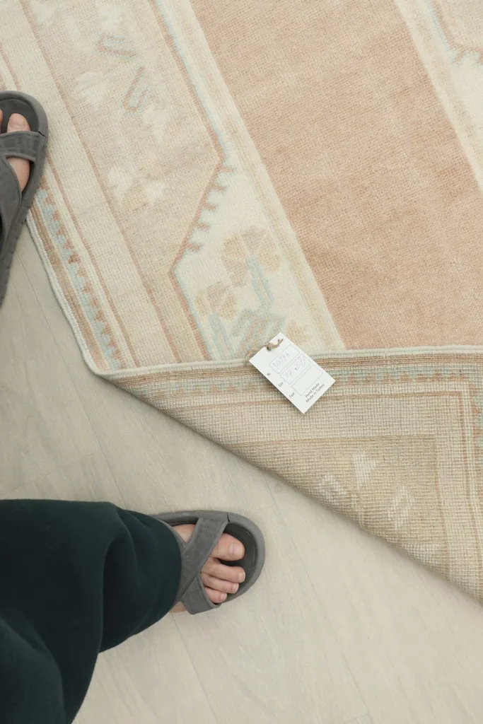 Overhead view with a foot for scale, showing the texture and a tag on the rug.