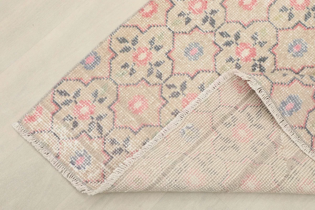 Folded corner of the rug revealing the cotton foundation and the reverse side of the hand-knotted construction.