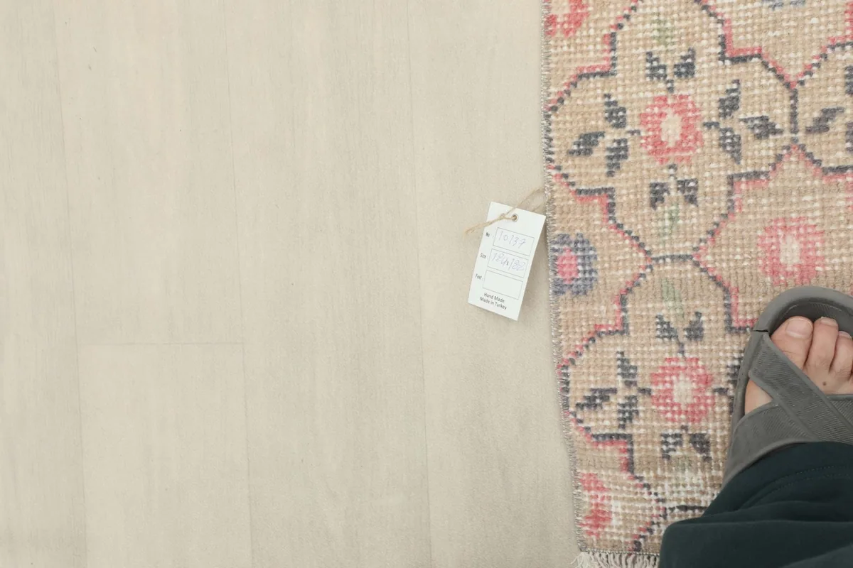 Overhead view of a foot next to the rug, showing a size tag and the rug's texture.