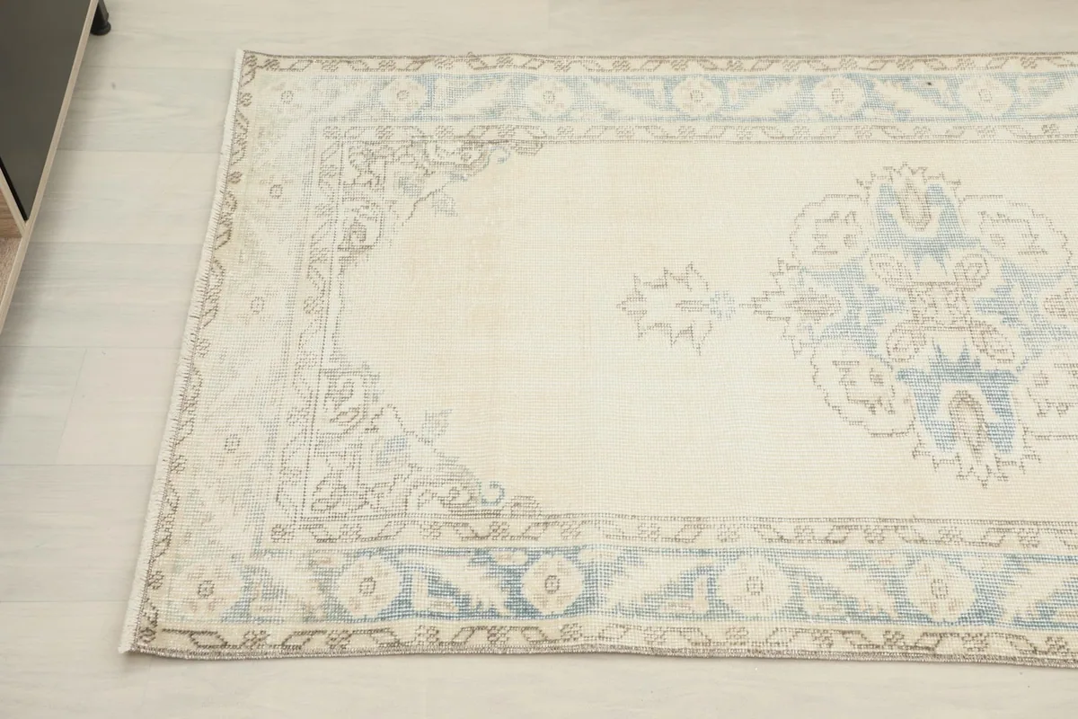 Detailed view of the rug's patterns and colors, highlighting the faded blue and tan motifs.