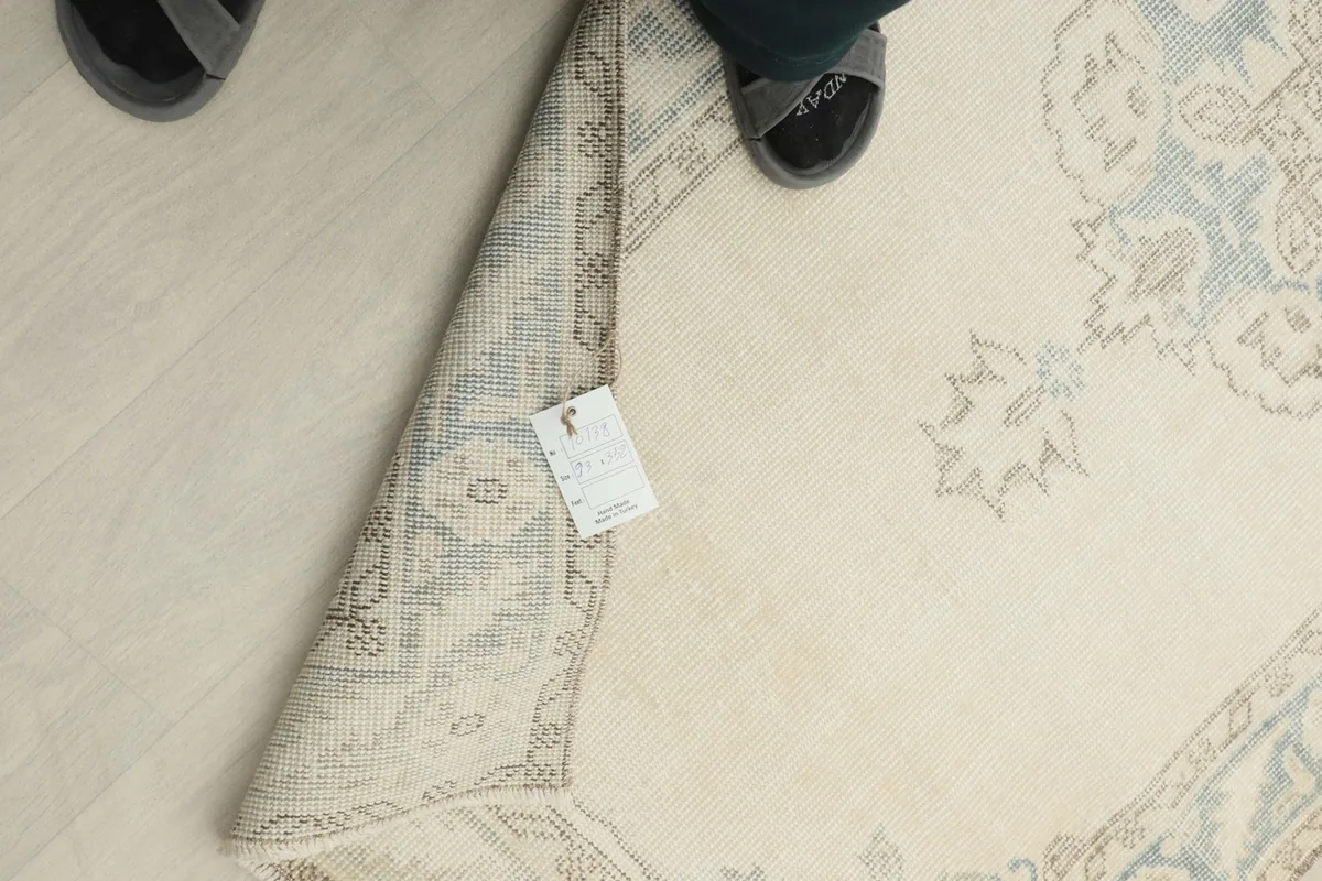 Overhead view of the rug's reverse side with a tag, showing the hand-knotted construction.