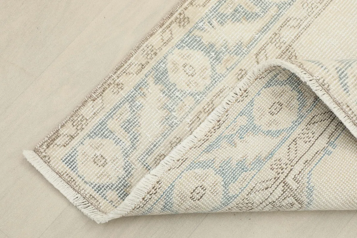 Corner of the rug folded back, revealing the cotton foundation and reverse side of the weave.