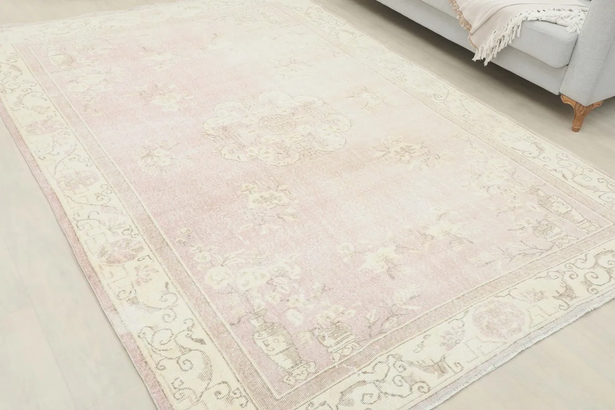 Wide angled shot of the large rose rug, showcasing its placement in a room with a sofa.