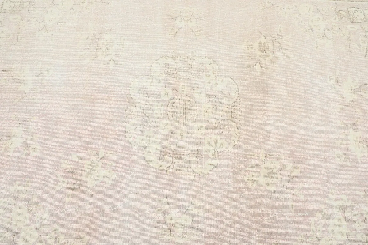 Detailed overhead view of the central medallion and surrounding faded floral patterns on the rose rug.