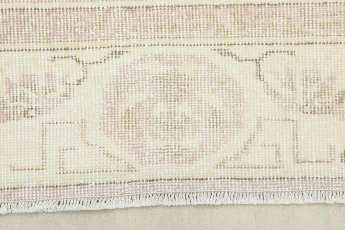 Detail of the ivory and beige border design with an inner rose band and outer fringe.