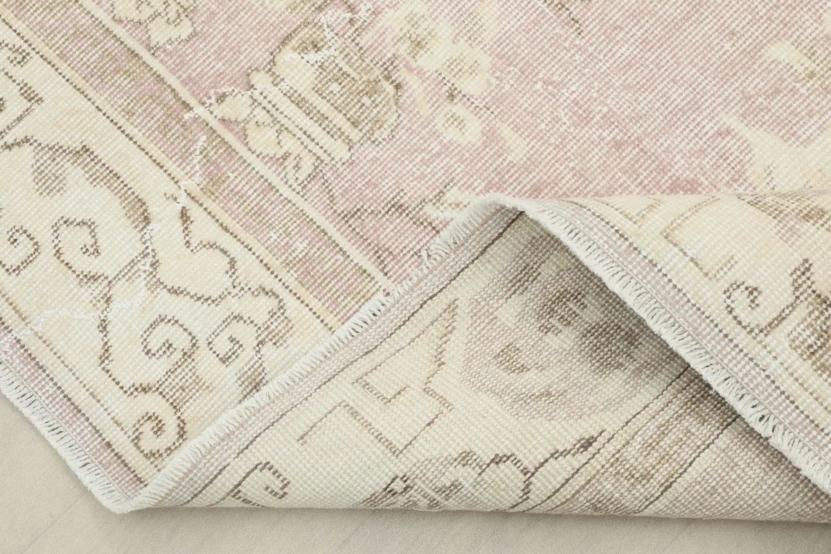 Corner of the rug folded back to reveal the cotton foundation and hand-knotted construction.